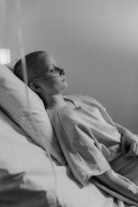 A thoughtful monochrome depiction of a patient resting in a hospital bed, illustrating themes of illness and recovery.